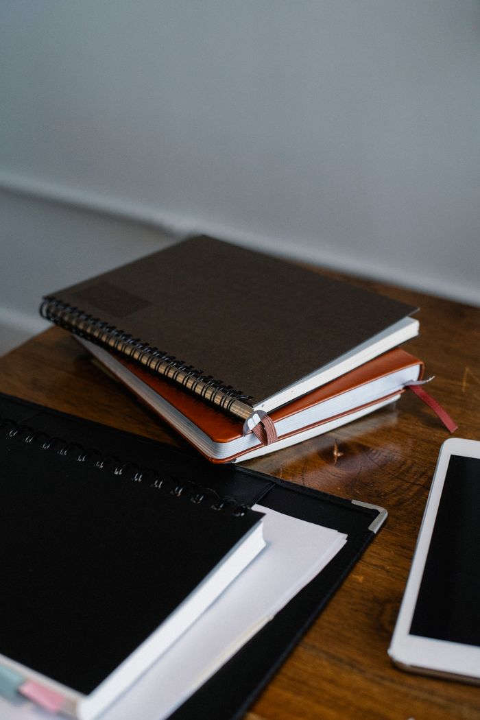 High angle of paper notebooks and modern tablet on wooden table in office