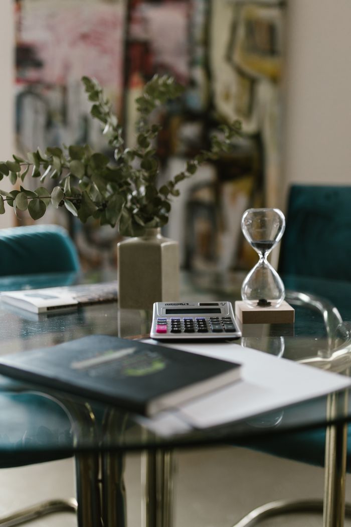 Sophisticated office table setup featuring hourglass, calculator, and decor.